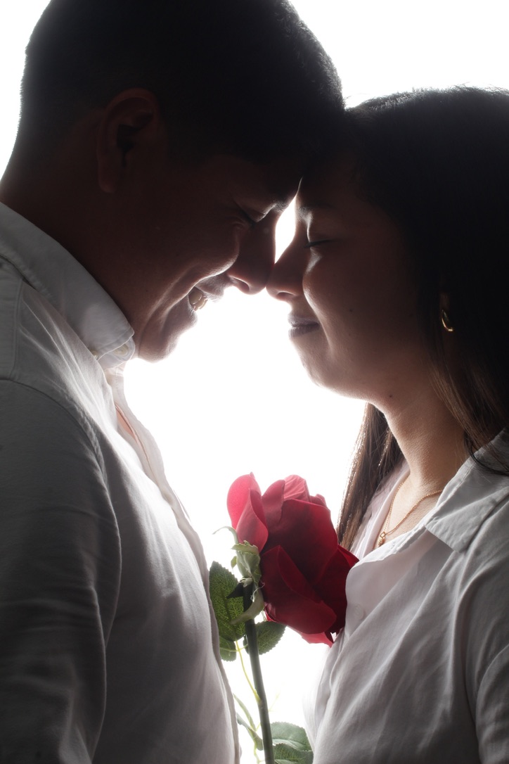 Junior y Diana, frente con frente, sosteniendo una rosa